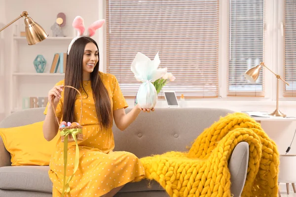 Tavşan kulaklı hamile bir kadın. Paskalya yumurtaları evdeki kanepede oturuyor.