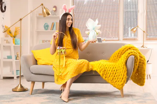 Tavşan kulaklı hamile bir kadın. Paskalya yumurtaları evdeki kanepede oturuyor.