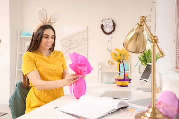 Evde paskalya hediyesi yumurtası olan tavşan kulaklı hamile bir kadın.