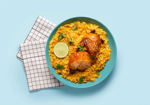 Mavi arka planda geleneksel tavuk biryani kasesi.
