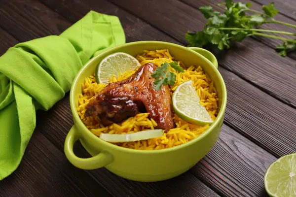 Ahşap arka planda geleneksel tavuk biryani kasesi.