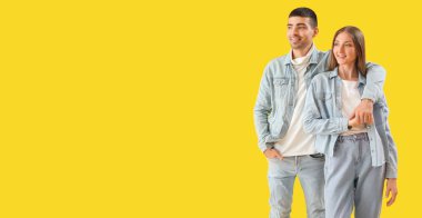 Sarı arka planda kot elbiseli şık genç bir çift, mesaj için yer var.