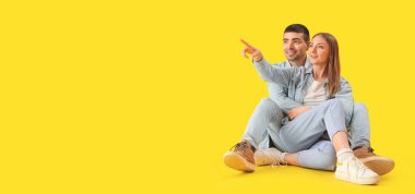 Sarı arka planda kot elbiseli şık genç bir çift, mesaj için yer var.