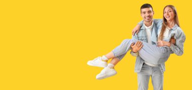 Sarı arka planda kot elbiseli şık genç bir çift, mesaj için yer var.