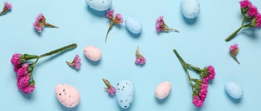 Açık mavi arkaplanda pek çok Paskalya yumurtası ve çiçek var.