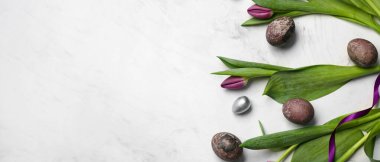 Paskalya yumurtaları ve çiçekler hafif arkaplanda ve metin için yer var