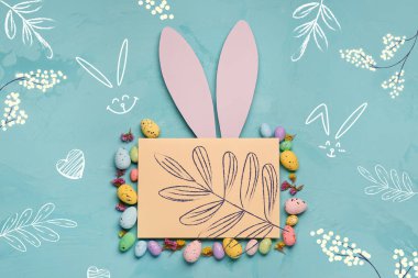 Yumurtalı, dallı ve açık mavi arka planda tavşan kulaklı Paskalya kompozisyonu