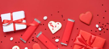 Kalp şeklinde kurabiyeler ve kırmızı arka planda hediyeler. Sevgililer Günü kutlaması