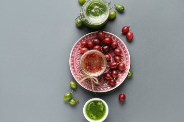 Gri arka planda lezzetli bektaşi üzümü reçeli olan kavanoz ve kase.