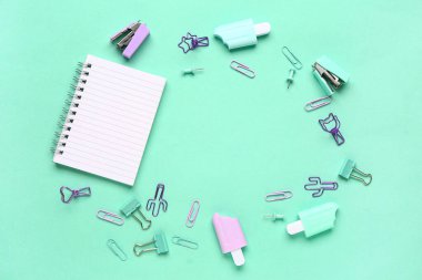 Turkuaz arka planda farklı kırtasiye malzemesi içeren defterden yapılmış çerçeve