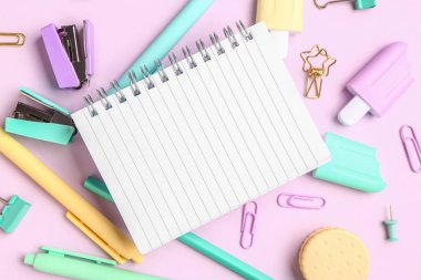 Pembe arka planda farklı kırtasiye malzemesi içeren defter.
