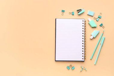 Turuncu arka planda farklı kırtasiye malzemesi içeren defter