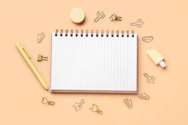 Turuncu arka planda farklı kırtasiye malzemesi içeren defter