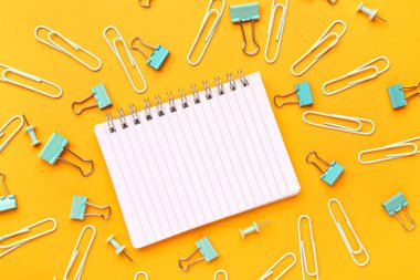 Turuncu arkaplanda not defteri ve ataç