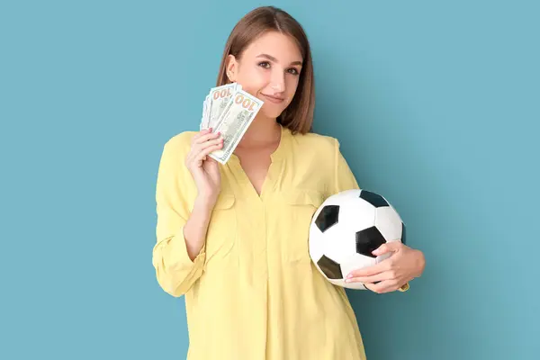 Young woman with soccer ball and money on blue background. Sports bet concept
