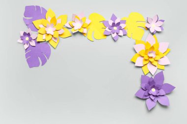 Renkli origami çiçeklerinden yapılmış çerçeve gri arkaplanda yapraklarla