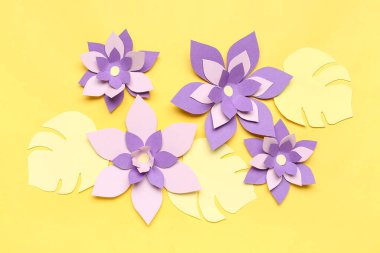 Sarı arka planda yaprakları olan renkli origami çiçekleri