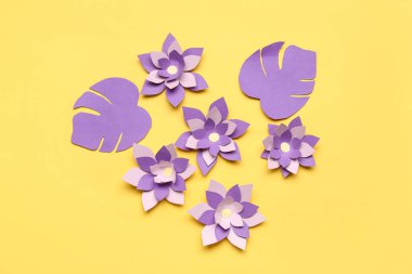 Renkli origami çiçekleri ve sarı arkaplanda yapraklar