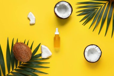 Sarı arka planda palmiye yaprakları olan bir şişe hindistan cevizi kozmetik yağı.