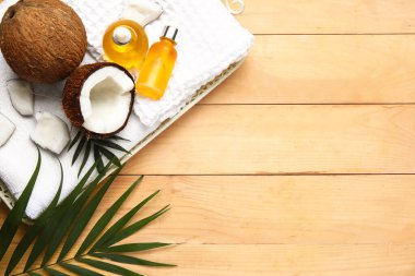 Bej ahşap arka planda banyo aksesuarları ile hindistan cevizi kozmetik yağı şişeleri