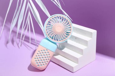 Portatif elektrikli vantilatör ve mor arka planda palmiye yaprağı ile sıva podyum, yakın plan