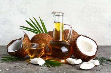 Duvarın yanındaki grunge grisi masada hindistan cevizi kozmetik yağı var.