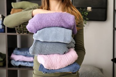 Evdeki oturma odasında şık giysileri olan genç bir kadın, yakın plan.