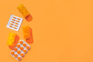 Tabletler ve haplar turuncu arka planda su topladı.