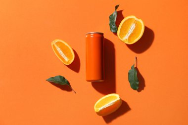 Olgun portakallı soda kutusu ve turuncu arka planda yeşil yapraklar.