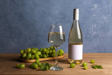 Ahşap arka planda boş etiketli üzüm ve şarap şişesi.