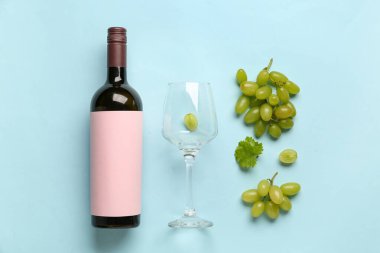 Boş etiketli bir şişe kırmızı şarap ve arka planda beyaz üzümler, üst görünüm