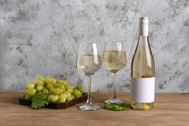 Ahşap arka planda boş etiketli üzüm ve şarap şişesi.