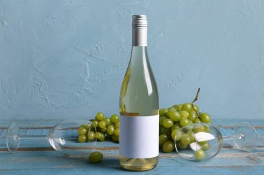 Mavi duvarın yanında üzümlü kadehler ve bir şişe nefis şarap.