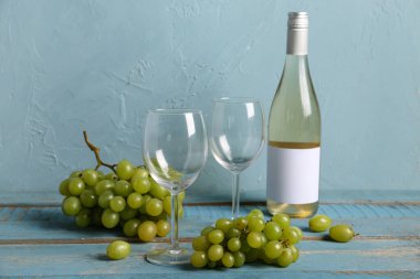 Mavi duvarın yanında üzümlü kadehler ve bir şişe nefis şarap.