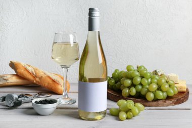 Üzümlü şarap, siyah havyar, tirbuşon ve ekmek beyaz duvarın yanındaki masada.