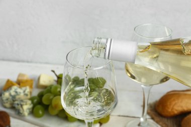 Beyaz şarap arka planda bardağa doluyor, yakın plan.