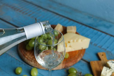 Arka planda beyaz şarap kadehe dökülüyor, yakın plan.