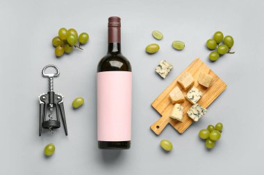 Boş etiketli bir şişe lezzetli şarap ve gri arka planda tirbuşon.