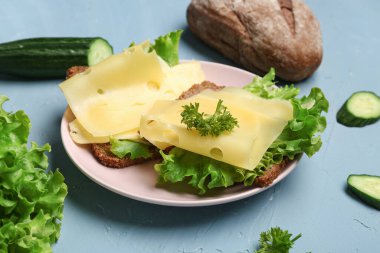 Peynirli ve marullu lezzetli sandviçler mavi arka planda, yakın plan.