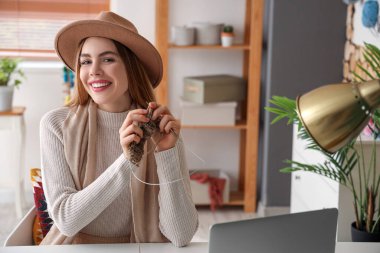 Evde iğnelerle örgü ören genç bir kadın.