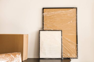 Ofisteki masada streç filme sarılı boş çerçeveler. Taşınma günü konsepti