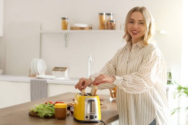 Genç, güzel, mutlu bir kadın mutfakta lezzetli tostlar yapıyor.