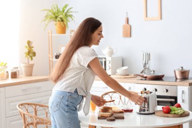 Genç, güzel, mutlu bir kadın mutfakta lezzetli tostlar yapıyor.