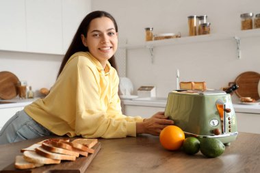 Genç, güzel, mutlu bir kadın mutfakta lezzetli tostlar yapıyor.