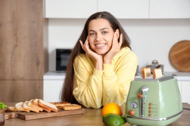 Genç, güzel, mutlu bir kadın mutfakta lezzetli tostlar yapıyor.