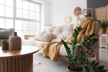 Işıl ışıl oturma odası, rahat beyaz kanepe, çiçek ve kahve masası.