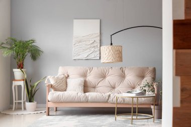 Modern oturma odasının içinde rahat beyaz kanepe, sehpa ve standart lamba var.