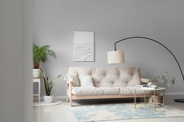 Modern oturma odasının içinde rahat beyaz kanepe, sehpa ve standart lamba var.