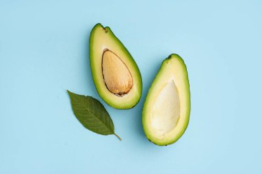 Taze taze avokado ve mavi arka planda yaprak.