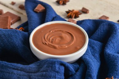 Beyaz ahşap arka planda lezzetli erimiş çikolatalı kase.